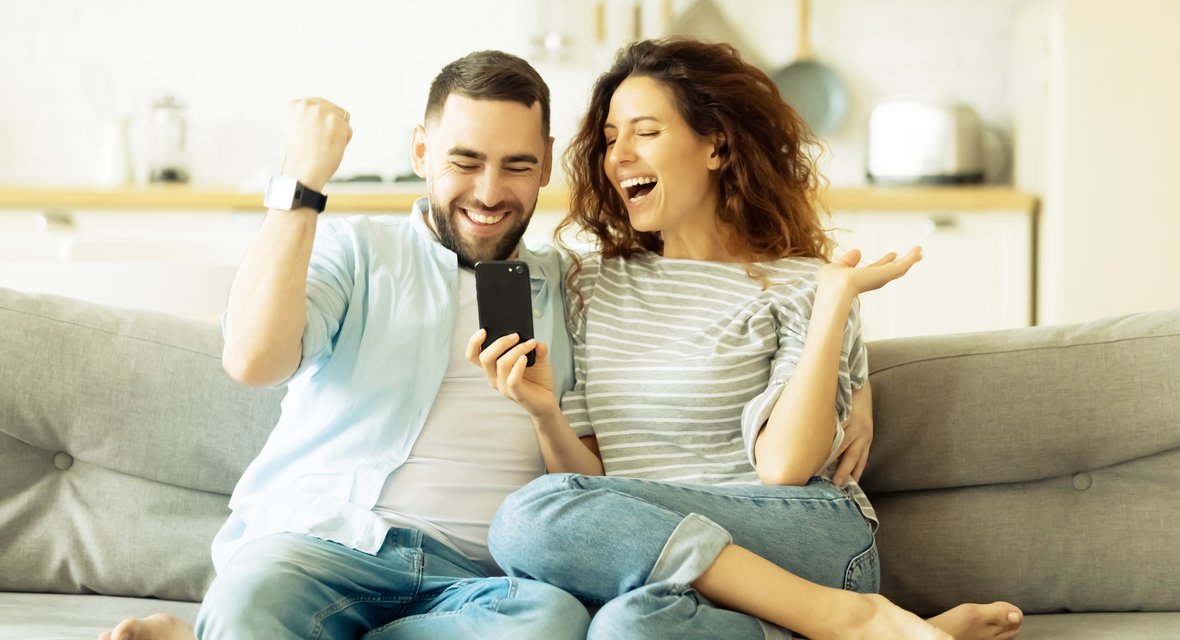 Symbolisches Bild mit zwei Personen vor Mobiltelefon freudig.